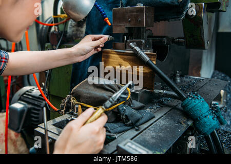 professional components factory female staff place parts in milling machine and holding pliers with selective focus photo. Stock Photo