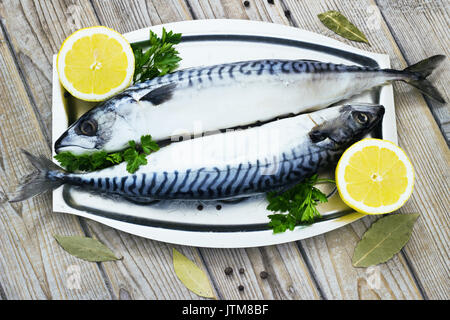 Mackerels fresh served on silver plate with lemon on a wooden background Stock Photo