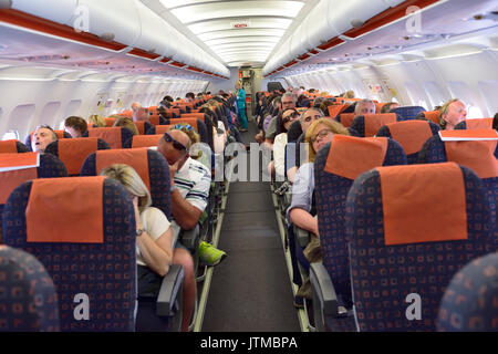 Inside commercial airplane cabin during flight with passengers mainly sleeping Stock Photo