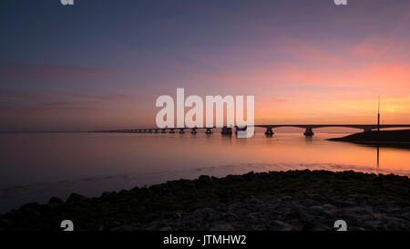 Sunset at the seemingly endless Zeeland Bridge, the longest bridge in the Netherlands with a length of 5.022 metres. Stock Photo