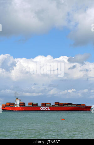 a very large container ship or vessel entering or leaving the port of Southampton docks carrying a cargo of boxes or containers loaded on deck or hold Stock Photo