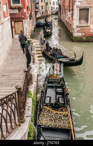 Two Gondoliers by their Gondolas by steps  in a Venetian canal. Stock Photo