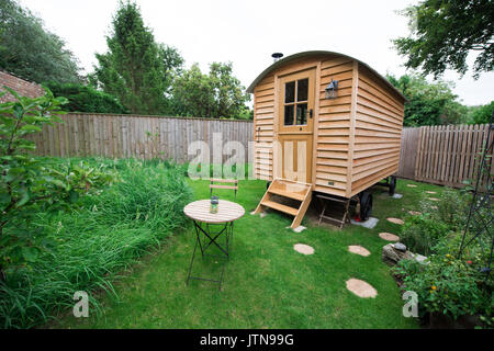 Hand built wooden shepherds' hut in a rural garden with a table and chairs    ready for holiday guests looking for cosy glamping in Suffolk, UK Stock Photo