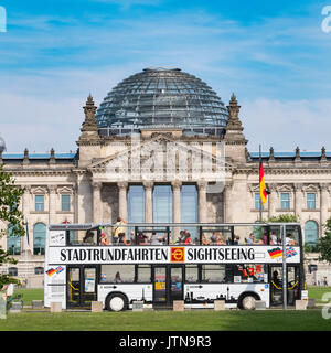 Tourist sightseeing city bus tour passes the German Reichstag parliament building in Berlin Germany Stock Photo