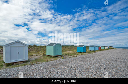 A ROW OF PASTEL COLOURED BEACH HUTS ON THE SAND AND SHINGLE BEACH FINDHORN MORAY SCOTLAND Stock Photo