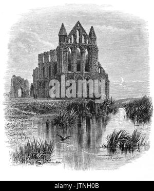 1870: Whitby Abbey in the moonlight. The 13th-century ruined Benedictine abbey overlooks the North Sea on the East Cliff above Whitby in North Yorkshire, England. It was dis-established during the Dissolution of the Monasteries- under the auspices of Henry VIII. Stock Photo