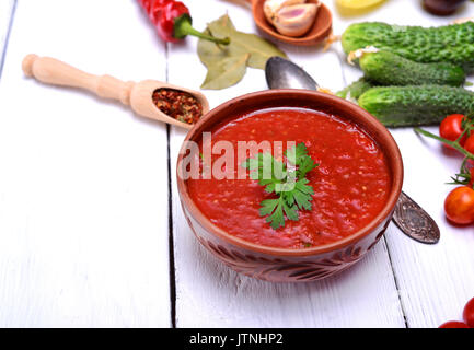 Cold gazpacho soup in a brown ceramic plate on a white wooden background, empty space on the left Stock Photo