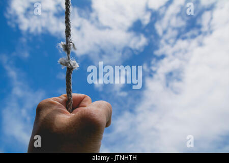 hand of man holding on to the rope it's almost absent under the sky. Stock Photo