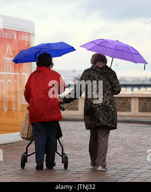 People walk along the promenade in Brighton, Sussex, as a yellow weather warning for rain has been issued for parts of the UK. Stock Photo