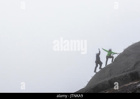 A man and a women slap a hi-five while doing the Via Ferrata on a rainy fall day in Squamish, British Columbia. Stock Photo