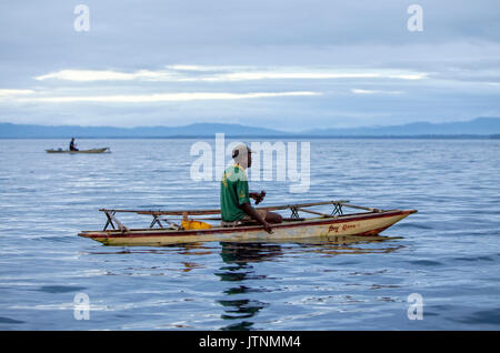 Early morning fishermen on outrigger canoe in the Alotau Bay. Alotau is the capital of Milne Bay Province, a province of Papua New Guinea. The town is located within the area in which the invading Japanese army suffered their first land defeat in the Pacific War in 1942, before the Kokoda Track battle. A memorial park at the old battle site commemorates the event. Alotau became the provincial capital in 1969 after it was shifted from Samarai. Alotau is the gateway to the Milne Bay Province which contains some of the most remote island communities in the world. Renowned for Stock Photo