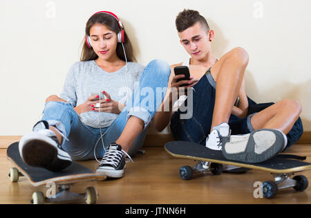 Girl and boy teens playing games online on smarthphones Stock Photo