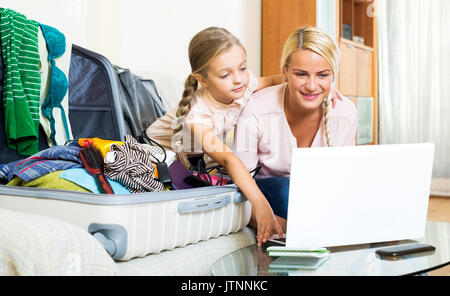 Happy young blonde mother and little daughter with luggage browsing web Stock Photo