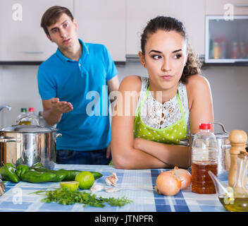 Young spanish family couple with serious faces quarrelling in kitchen . focus on woman Stock Photo