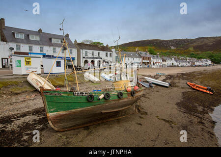Picturesque Scottish coastal town of Ullapool with white painted buildings and boats in harbour beside main street Stock Photo
