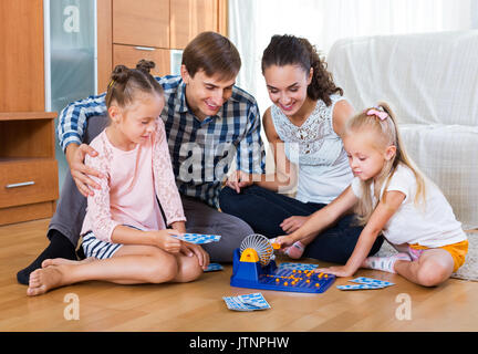 Cheerful parents and daughters with toy lotto at home Stock Photo