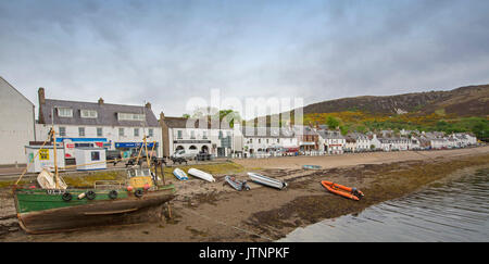 Panoramic view of Scottish coastal town of Ullapool with white painted shops and houses and boats in harbour beside main street Stock Photo
