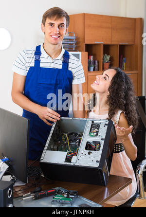 Smiling young longhaired woman and PC engineer repairing her broken computer Stock Photo