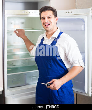 Serviceman fixing technical problems with fridge inside Stock Photo