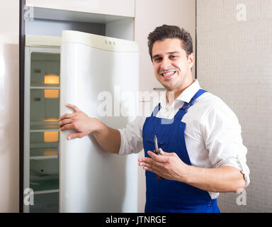 handyman fixing technical problems with fridge at residential lot Stock Photo