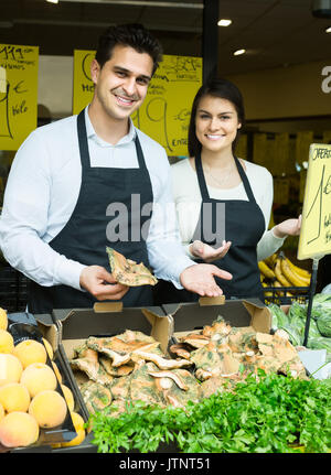 russian salespeople with farm mushrooms in market, prices are on Spanish Stock Photo