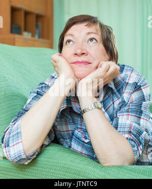 Portrait of sad senior female having tough time and laying on couch Stock Photo