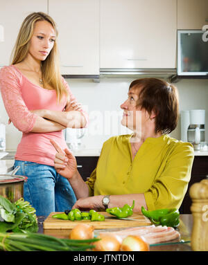 mother and adult daughter  having serious conversation in kitchen. Focus on mature Stock Photo