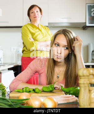 Mature mother and sad adult daughter having quarrel   in kitchen Stock Photo
