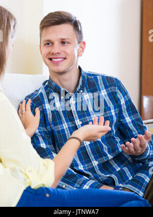 Cheerful young guy having positive conversation with his girlfriend indoors Stock Photo