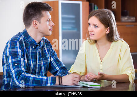 Two young collegues working with documents together in office Stock Photo