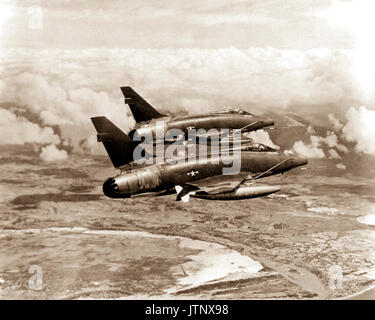An air-to-air right rear view of two F-100D Super Sabre aircraft streaking over South Vietnam on their way to an assigned target.  The aircraft provides much of the tactical air support to Allied ground forces fighting in Vietnam. Stock Photo