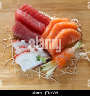 Assorted sashimi displayed on wooden cutting board. Stock Photo