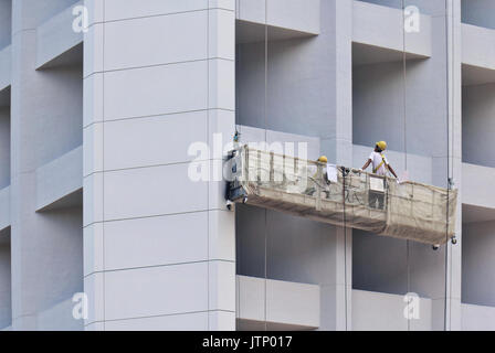 Construction workers in lift hanging from the building Stock Photo