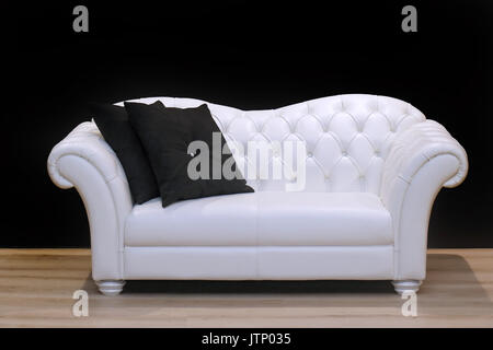 White leather sofa on wooden floor inside black wall interior Stock Photo