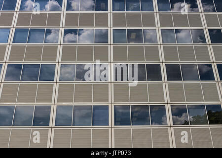 Ft. Wayne - Circa August 2017: Side of a skyscraper building with gray panels and windows that reflect the sky with clouds I Stock Photo