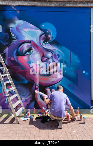 Artist Mr. Cenz spraying a commissioned street art work in Southend-on-Sea as part of the Estuary Fringe Fesival, England, UK Stock Photo