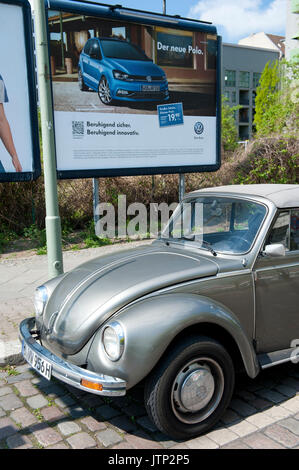 A vintage Volkswagen Beetle parked next to a modern VW Polo advertisement, Berlin, Germany Stock Photo