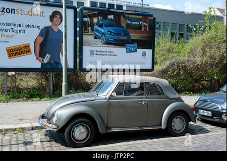 A vintage Volkswagen Beetle parked next to a modern VW Polo advertisement, Berlin, Germany Stock Photo