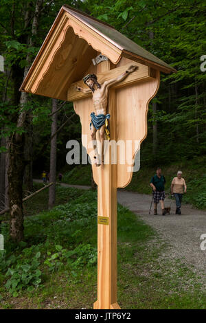 Carved wooden Jesus on the crucifix in a wood shelter by the path around lake Eibsee, Bavaria, germany Stock Photo