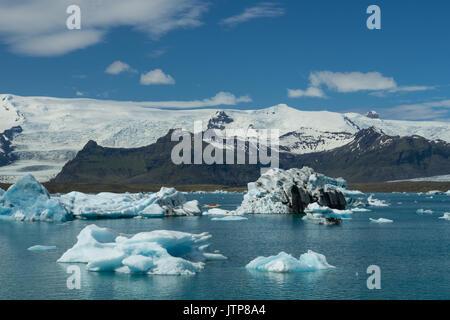 Iceland - Giant ice floes with boat between and glacier mountains in background Stock Photo