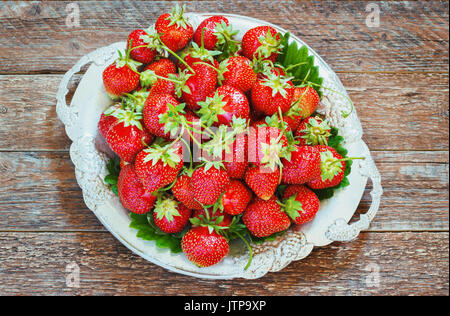 Fresh and delicious organic strawberries on old metal plate, on wooden table. Perfect for your healthy eating and dieting. Selective focus. Natural su Stock Photo