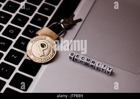 Cryptocurrency physical gold peercoin coin on the computer keyboard near padlock. Peercoin security concept. Stock Photo