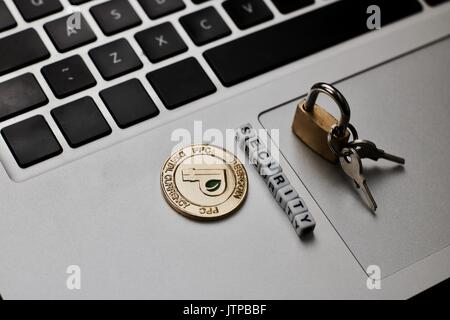 Cryptocurrency physical gold peercoin coin on the computer keyboard near padlock. Peercoin security concept. Stock Photo