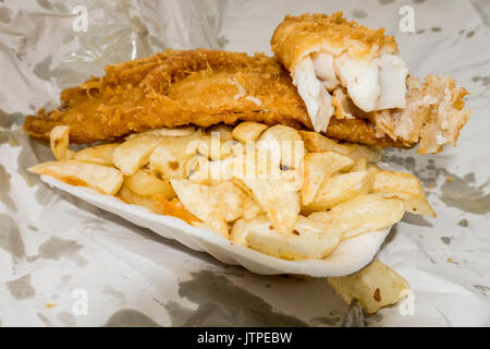 Traditional British fast food takeaway meal of battered fish and chips, in the container and paper wrapping. Stock Photo