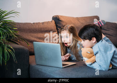adorable shocked girl and boy using laptop at home Stock Photo