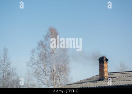 Smoking pipe on a snowy roof in a cold winter day Stock Photo