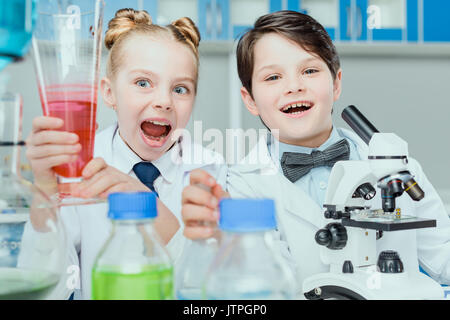 Little scientists in white coats making experiment with reagents and microscope in science laboratory Stock Photo