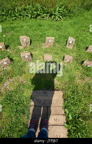 Shadow of an adult man male acts as the gnomon on a human sundial. Shadow cast on dial of stones. Two rows of stones for Daylight Saving Time DST. Stock Photo