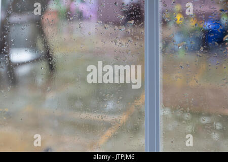 Raindrops Running Down a Window with a View Outside onto a Patio Stock Photo