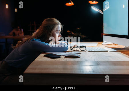 side view of exhausted businesswoman looking at computer screen at workplace Stock Photo